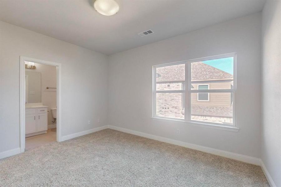 Unfurnished bedroom featuring light colored carpet and connected bathroom