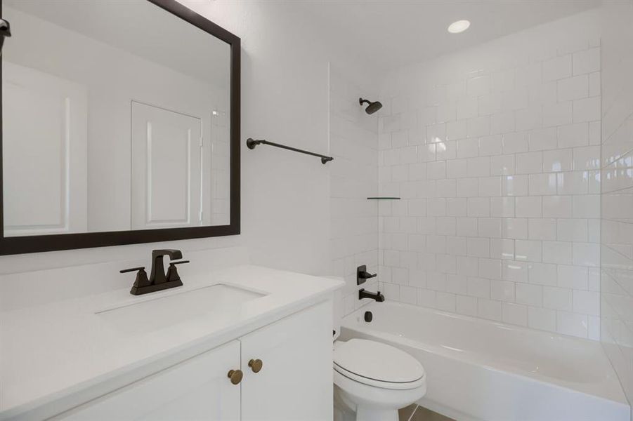 White vanity with integrated sink and dark bronze fixtures, framed mirror, and recessed lighting White vanity with integrated sink and dark bronze fixtures, framed mirror, and recessed lighting