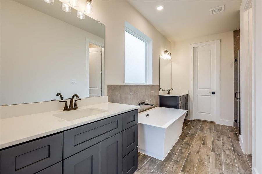 Double vanities in a dark color really anchor the room with the baththub front and center!