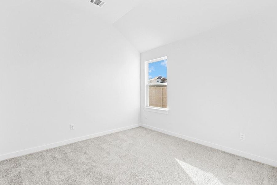 Carpeted spare room with vaulted ceiling and baseboards