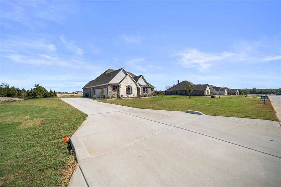 View of front of property featuring driveway, a front lawn, a garage, and brick siding View of front of property featuring driveway, a front lawn, a garage, and brick siding