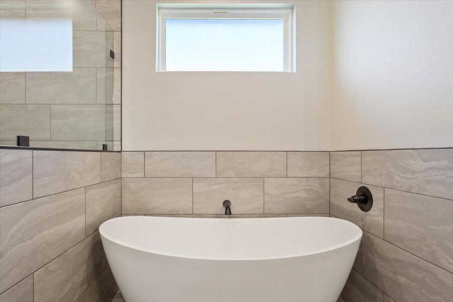 Bathroom with a freestanding bath, tile walls, and plenty of natural light