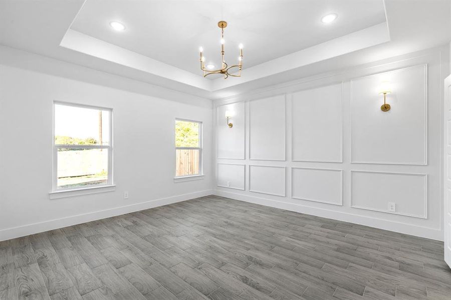 Master bedroom featuring a tray ceiling, hardwood / wood-style floors, and a chandelier