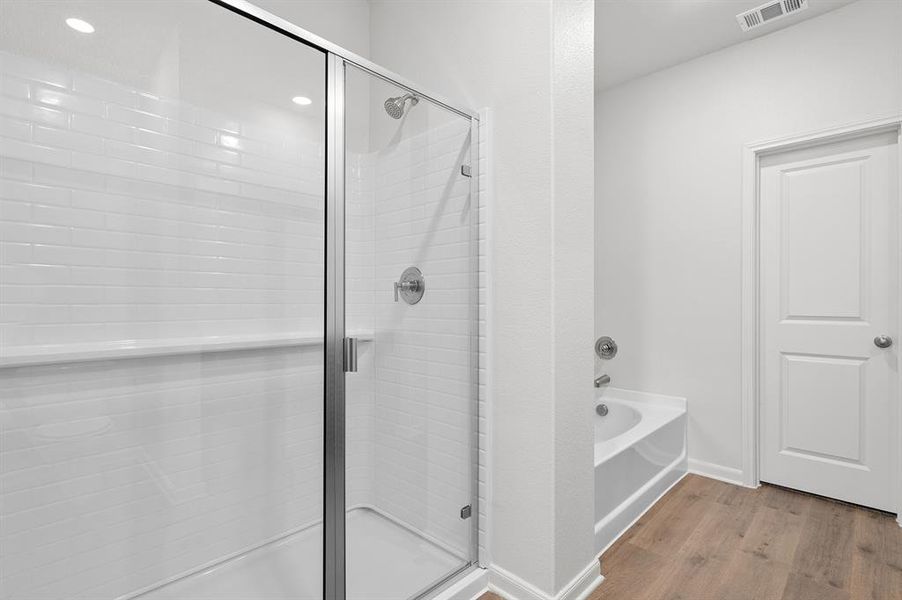 Full bath with a bath, a stall shower, wood finished floors, and recessed lighting