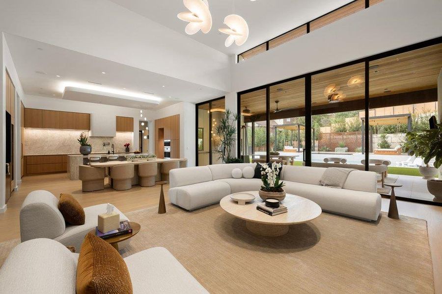 Spacious open-concept living area featuring high ceilings, wood-finish flooring, and expansive floor-to-ceiling glass doors