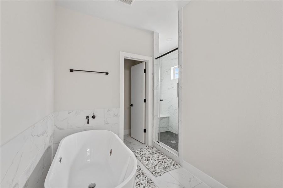 Modern bathroom with freestanding tub, and a glass-enclosed shower. Clean, minimalistic design with neutral colors.