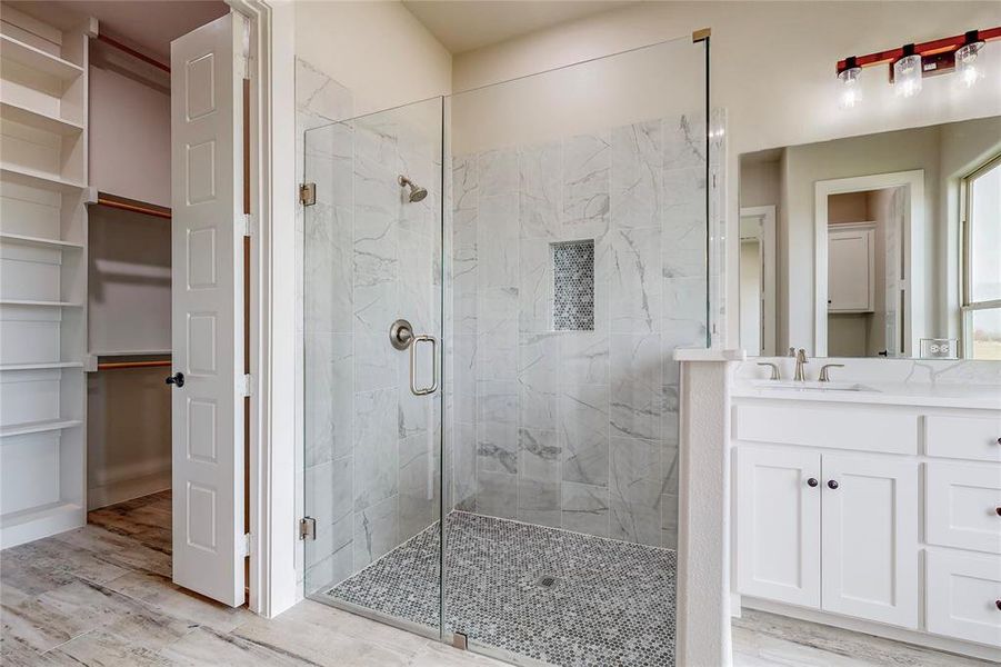 Bathroom with vanity, a shower with shower door, and wood-type flooring