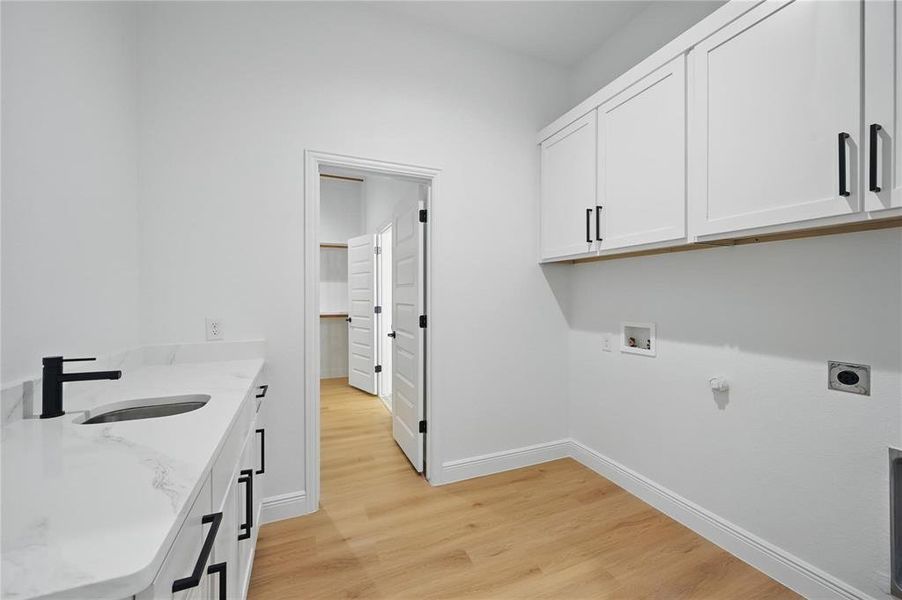 Washroom with cabinet space, light wood-type flooring, washer hookup, and hookup for an electric dryer Washroom with cabinet space, light wood-type flooring, washer hookup, and hookup for an electric dryer