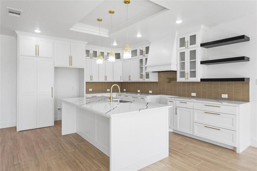 Kitchen with glass insert cabinets, a tray ceiling, recessed lighting, white cabinets, and wood finish floors Kitchen with glass insert cabinets, a tray ceiling, recessed lighting, white cabinets, and wood finish floors