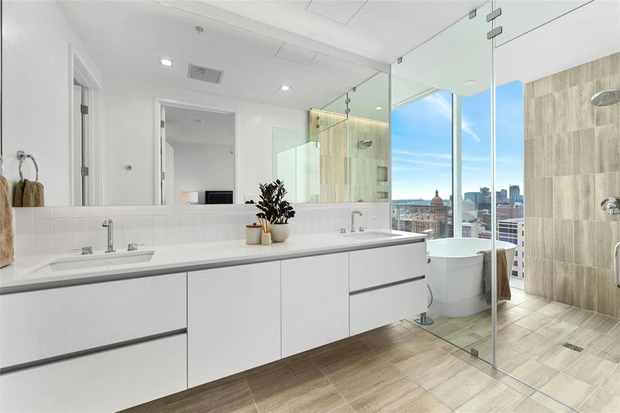 The primary bathroom boasts a dual vanity with cabinets, a frameless glass shower, and a bathtub. Enjoy the city view while soaking in the bathtub, surrounded by floor-to-ceiling windows that fill the space with natural light and offer a stunning urban backdrop. The primary bathroom boasts a dual vanity with cabinets, a frameless glass shower, and a bathtub. Enjoy the city view while soaking in the bathtub, surrounded by floor-to-ceiling windows that fill the space with natural light and offer a stunning urban backdrop.