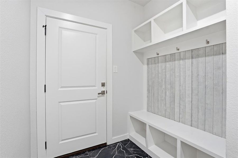 Built-in storage bench featuring cubbies, upper shelving, and wall-mounted hooks