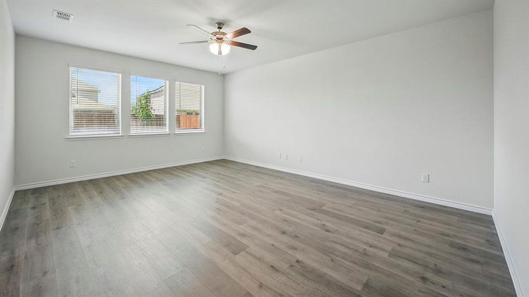 Spacious room featuring wood-finish flooring, white baseboards, and bright white walls