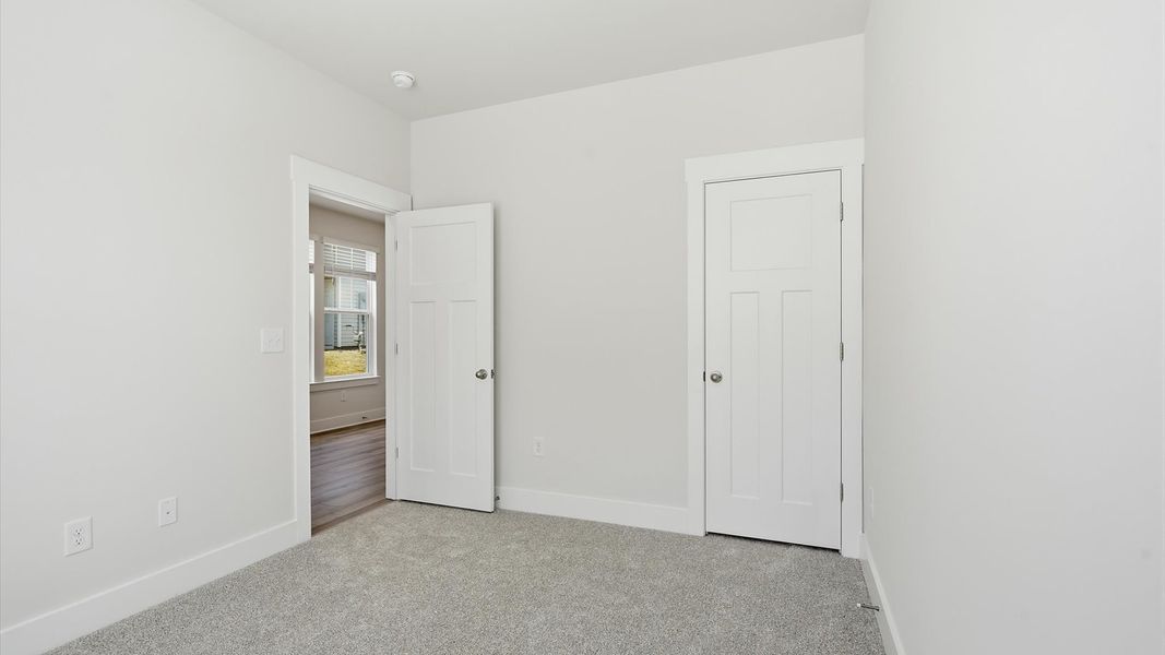 Tasteful secondary bedroom with plush carpet and a spacious walk-in closet at the Clarke Townes community
