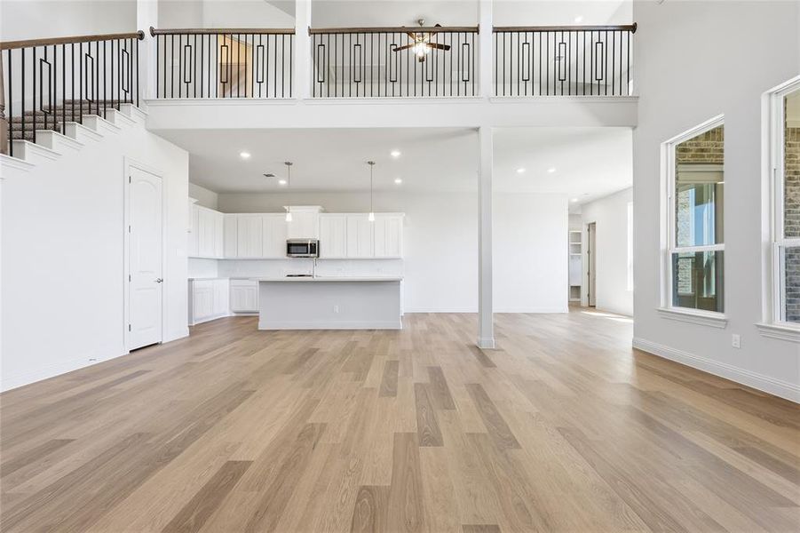 Unfurnished living room featuring light wood-style floors, recessed lighting, and a high ceiling