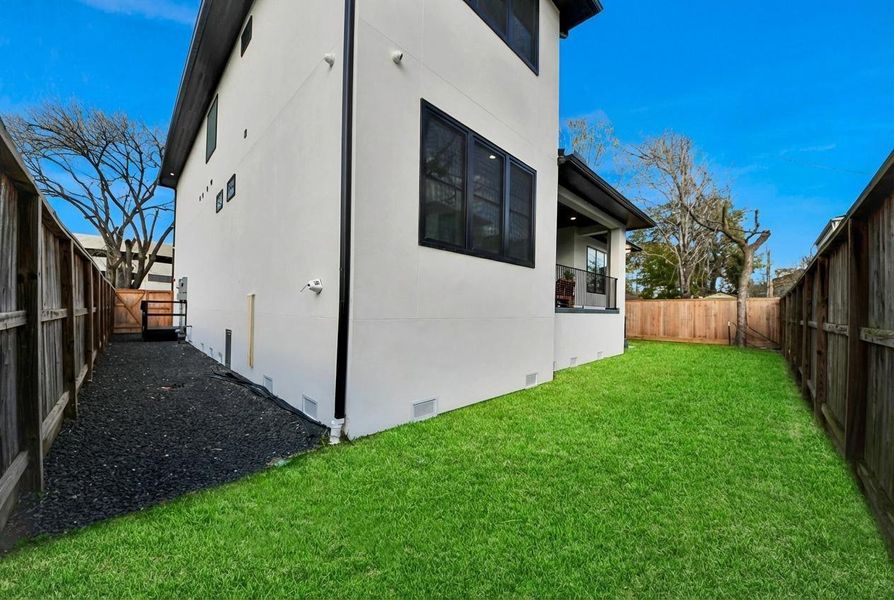 A gravel pathway runs along the backyard’s side, offering both functionality and a refined, low-maintenance touch to the outdoor area.