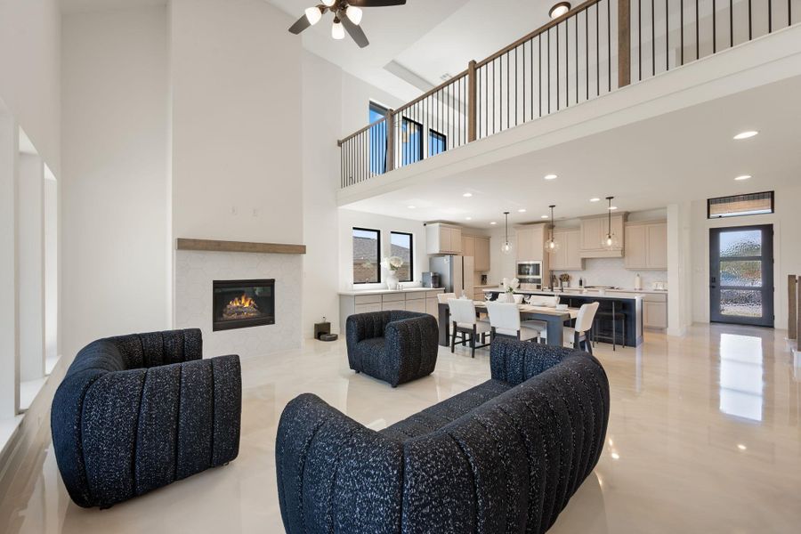 An open-concept living area boasts high ceilings, a cozy fireplace, and an adjacent modern kitchen with an inviting island. An open-concept living area boasts high ceilings, a cozy fireplace, and an adjacent modern kitchen with an inviting island.