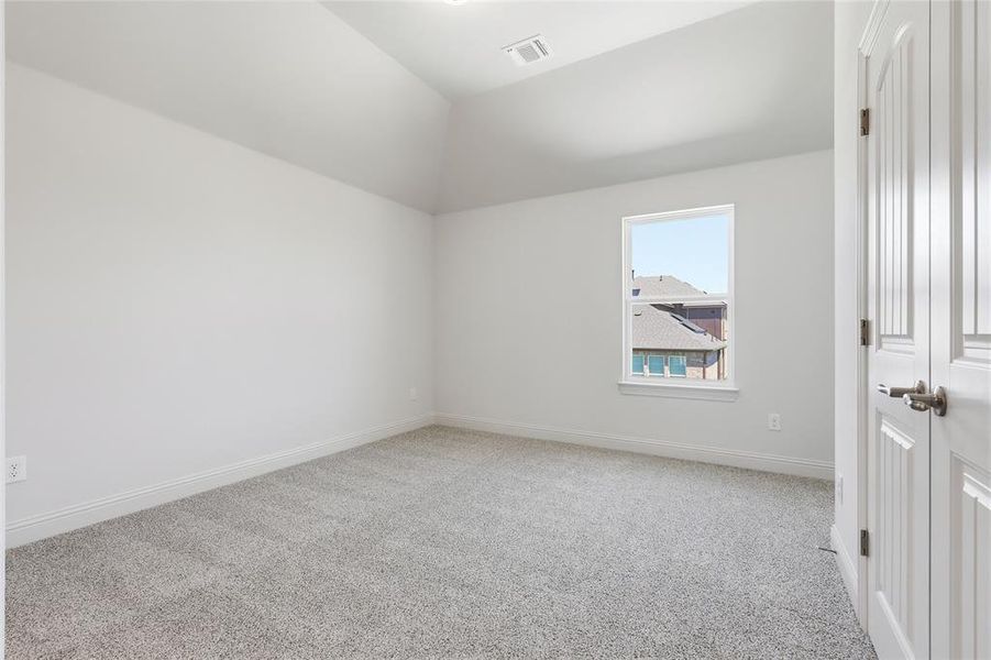 Empty room featuring light colored carpet and vaulted ceiling