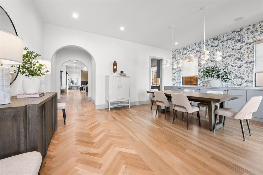 Dining room featuring parquet flooring, arched walkways, wallpapered walls, and suspended lighting