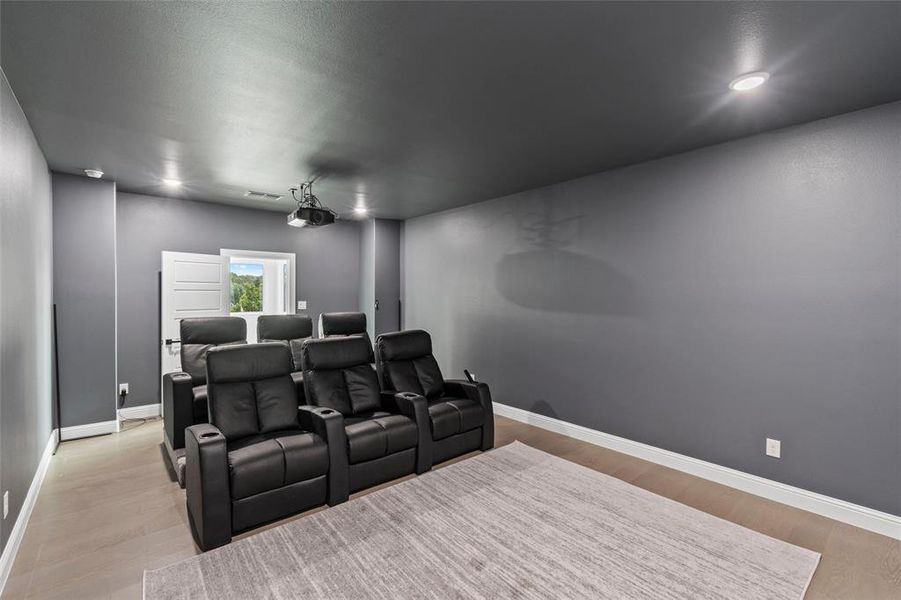 Cinema room with light wood-type flooring