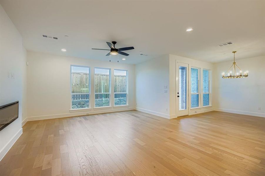 Unfurnished living room with healthy amount of natural light, light wood-type flooring, recessed lighting, a chandelier, and ceiling fan Unfurnished living room with healthy amount of natural light, light wood-type flooring, recessed lighting, a chandelier, and ceiling fan