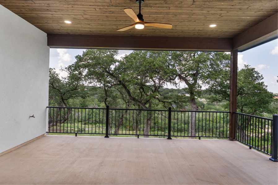 A spacious covered deck extends outward, offering elevated views of the verdant tree-filled landscape.