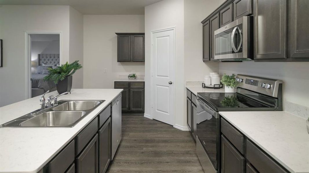 Modern kitchen featuring a double basin stainless steel sink, a stainless steel dishwasher, and dark wood-finish cabinetry Modern kitchen featuring a double basin stainless steel sink, a stainless steel dishwasher, and dark wood-finish cabinetry