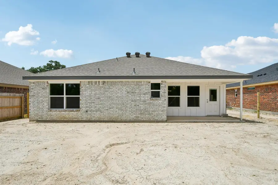 A newly constructed residence features a crisp brick facade and a shaded concrete patio area. A newly constructed residence features a crisp brick facade and a shaded concrete patio area.