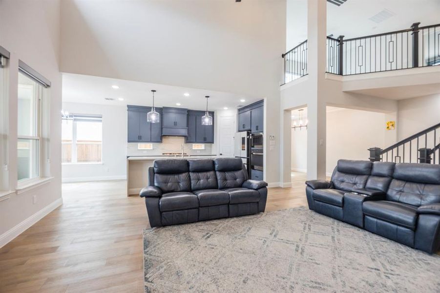 Living room with light wood-style flooring, baseboards, and a towering ceiling