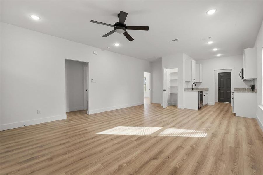 Unfurnished living room with ceiling fan, sink, and light hardwood / wood-style flooring