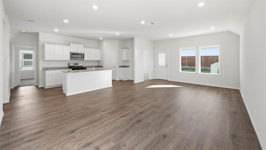 Kitchen featuring white cabinets, open floor plan, stainless steel appliances, dark wood-style flooring, and a center island with sink Kitchen featuring white cabinets, open floor plan, stainless steel appliances, dark wood-style flooring, and a center island with sink