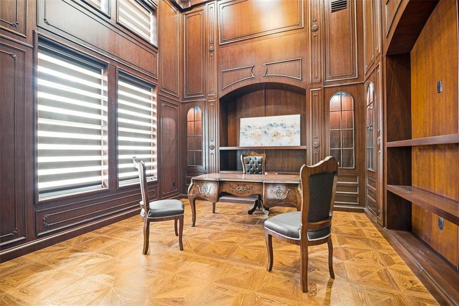 Custom wood paneling, parquet wood-finish flooring, built-in shelving, high ceilings, and arched accents define this elegant interior space
