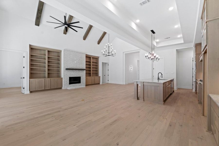 Unfurnished living room featuring a fireplace, light wood-type flooring, recessed lighting, a chandelier, and a ceiling fan Unfurnished living room featuring a fireplace, light wood-type flooring, recessed lighting, a chandelier, and a ceiling fan