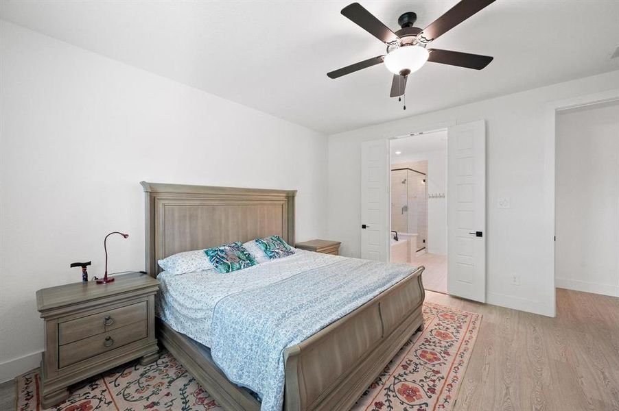 Bedroom featuring light wood-finish flooring, white walls, and a ceiling fan with integrated lighting Bedroom featuring light wood-finish flooring, white walls, and a ceiling fan with integrated lighting