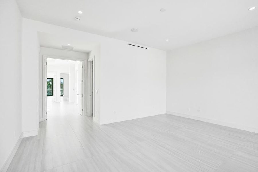 Expansive primary retreat occupying nearly half of the second floor, featuring high ceilings, modern linear A/C vents, dual walk-in closets, and an oversized east-facing covered balcony and east-facing covered balcony with TV and spa connections.