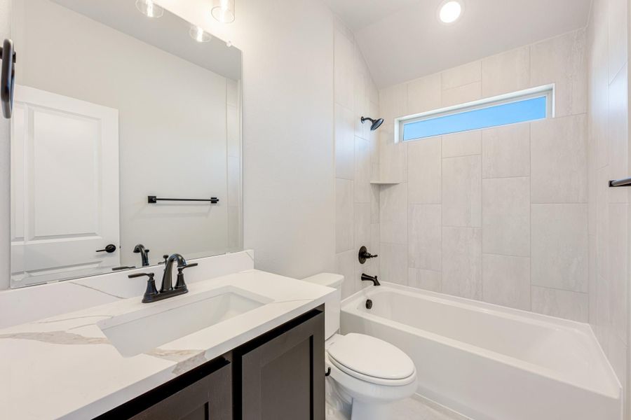 Bathroom with white quartz vanity, dark fixtures, tiled tub-shower combo, and small window above tub Bathroom with white quartz vanity, dark fixtures, tiled tub-shower combo, and small window above tub
