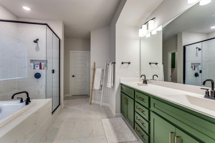 Bathroom featuring a garden tub, marble finish floor, a stall shower, and a sink