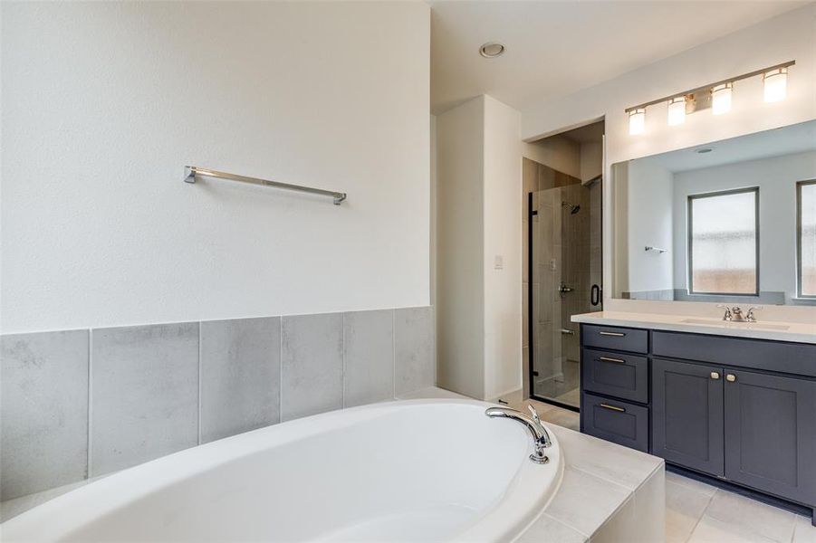 Full bath featuring a stall shower, vanity, a garden tub, and light tile patterned floors