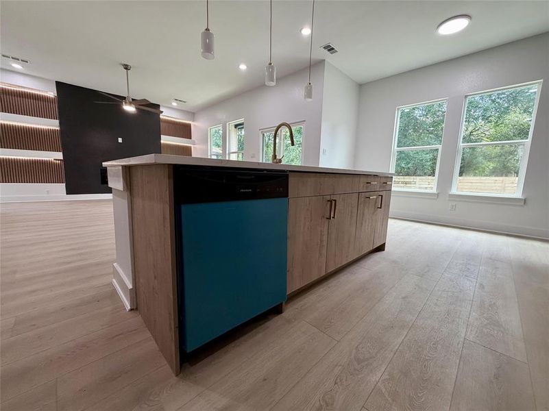 Kitchen island featuring wood-finish cabinetry, a brass-finish faucet, and pendant lighting Kitchen island featuring wood-finish cabinetry, a brass-finish faucet, and pendant lighting