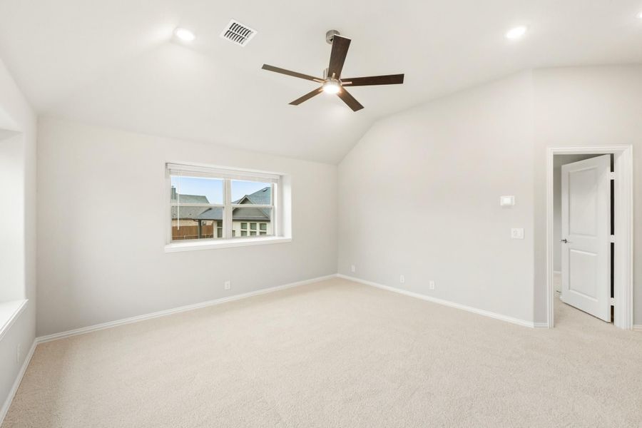 Empty bedroom with vaulted ceiling, ceiling fan, carpet flooring, and a single window Empty bedroom with vaulted ceiling, ceiling fan, carpet flooring, and a single window