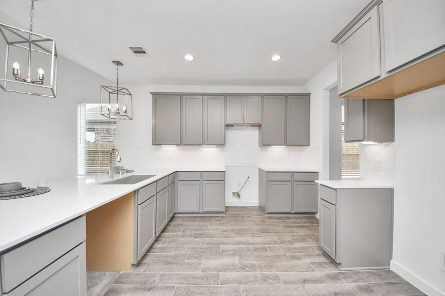 The kitchen is a culinary haven, featuring granite countertops, a tile backsplash, stainless steel appliances, 42” upper cabinets, and undercabinet lighting. Sample photo of completed home with similar floor plan. Actual colors and selections may vary.