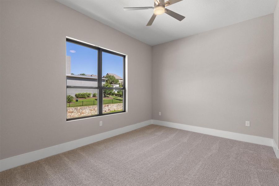 A well-lit bedroom features plush carpeting and a modern ceiling fan, offering tranquil views. A well-lit bedroom features plush carpeting and a modern ceiling fan, offering tranquil views.