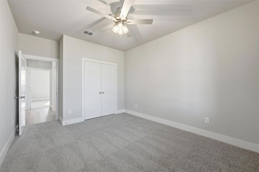Unfurnished bedroom featuring carpet, a ceiling fan, and a closet