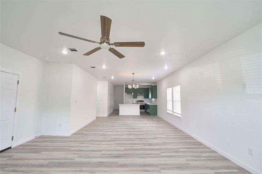 Open-concept living space featuring wood-finish flooring, a contemporary ceiling fan, and recessed lighting