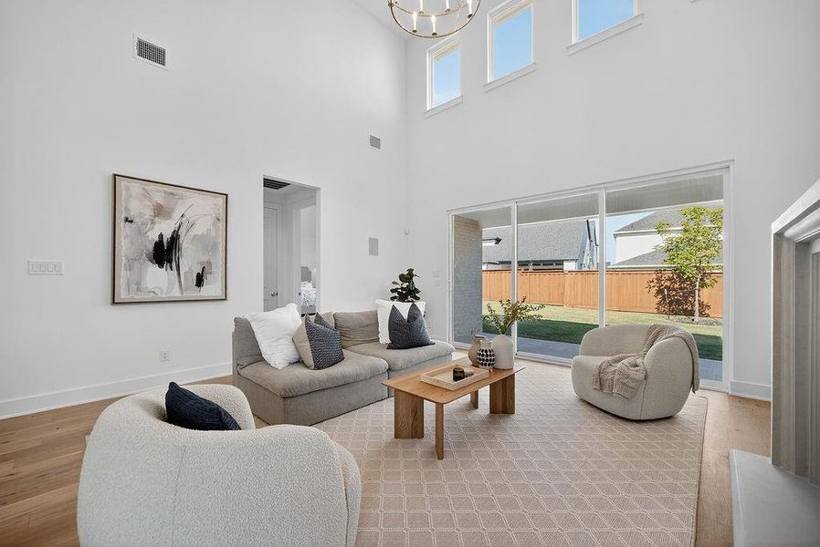 Living area featuring light wood-style floors, a high ceiling, and a chandelier Living area featuring light wood-style floors, a high ceiling, and a chandelier