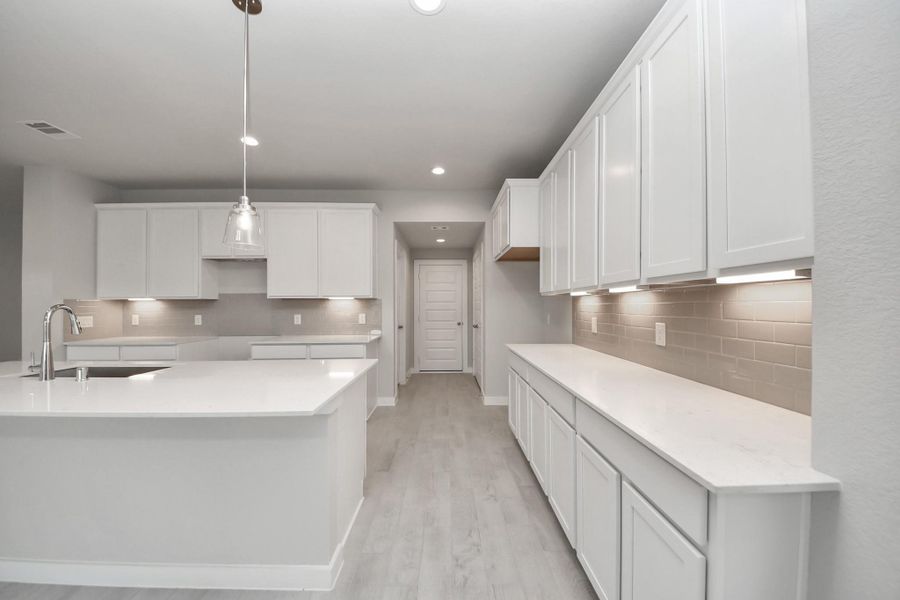 Step into the dream kitchen you've always wanted! This generously spacious culinary haven features a massive granite island, high ceilings, soft-close cabinets, granite countertops, stainless steel appliances, a sleek tile backsplash, and recessed lighting. Sample photo of completed home with similar floor plan. Actual colors and selections may vary. Step into the dream kitchen you've always wanted! This generously spacious culinary haven features a massive granite island, high ceilings, soft-close cabinets, granite countertops, stainless steel appliances, a sleek tile backsplash, and recessed lighting. Sample photo of completed home with similar floor plan. Actual colors and selections may vary.