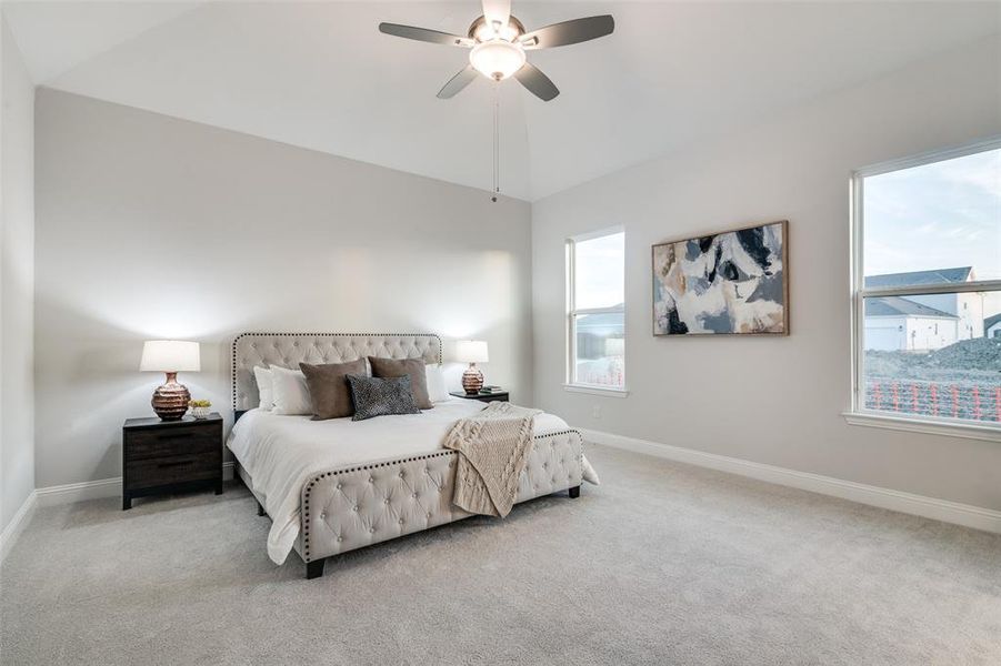 Bedroom featuring multiple windows, ceiling fan, light colored carpet, and lofted ceiling