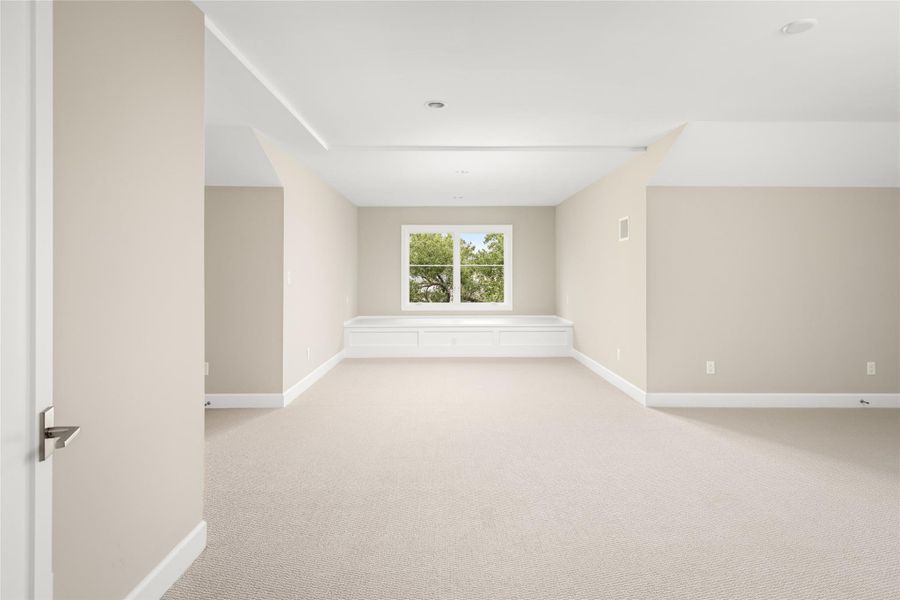 A thoughtfully designed third-floor retreat featuring a flexible footprint and a cozy window seat framed by treetop views.