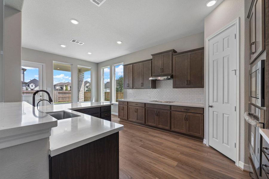 This light and bright kitchen features quartz countertops, dark stained cabinets, a large sink overlooking your family room, recessed lighting, and beautiful backsplash. This light and bright kitchen features quartz countertops, dark stained cabinets, a large sink overlooking your family room, recessed lighting, and beautiful backsplash.