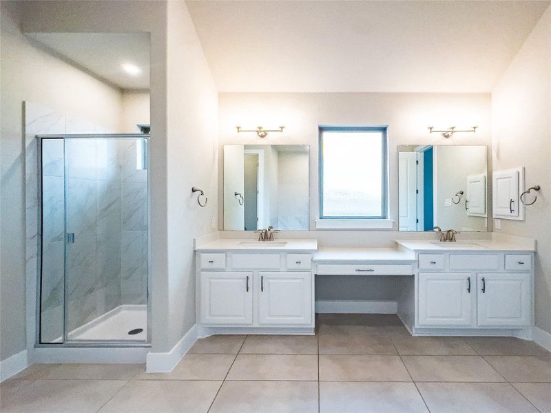 Bathroom featuring double vanity, a marble finish shower, and light tile patterned floors Bathroom featuring double vanity, a marble finish shower, and light tile patterned floors