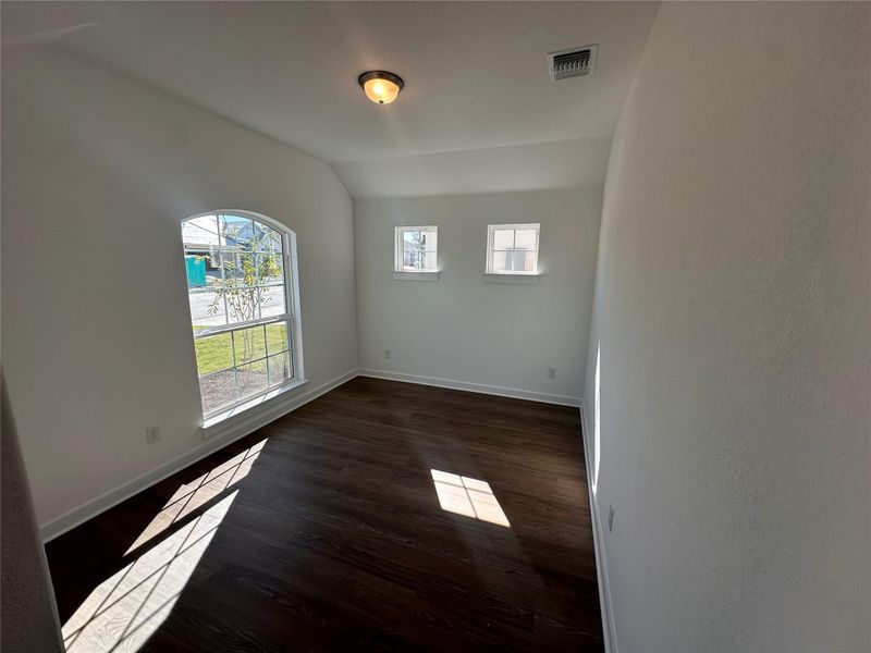 Empty room with dark wood-type flooring and lofted ceiling Empty room with dark wood-type flooring and lofted ceiling